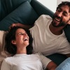 Lifestyle photo of a man and woman laughing on a couch